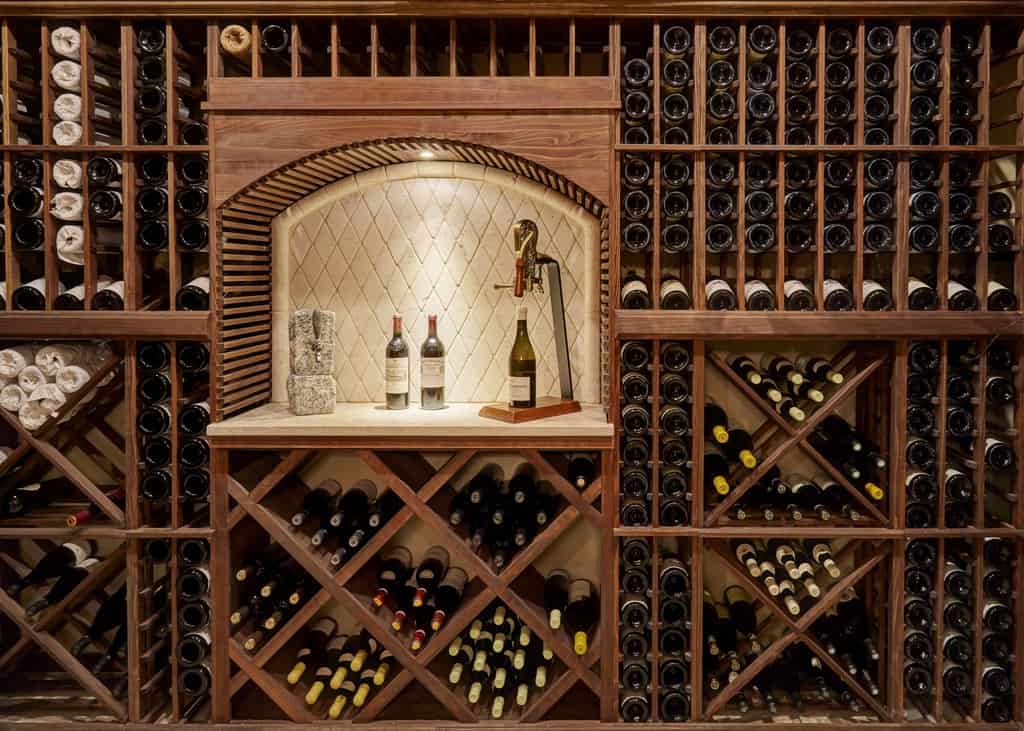 A custom wooden wine cellar with wooden racks and a built-in table insert to sample wine.