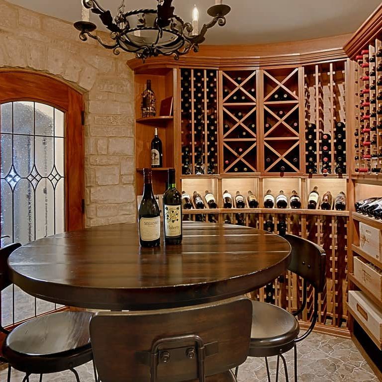 A rounded hardwood table surrounded by a custom wine cellar with circular walls and overhead lightingwine cellar.