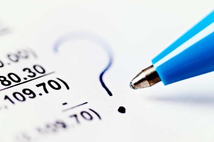 Macro ballpoint pen marks financial document with question mark