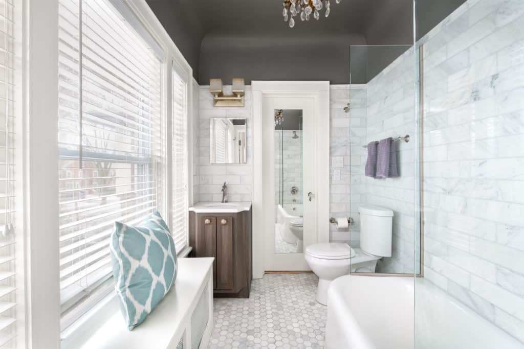 A jack and jill bathroom with marble hex tiles on the floor and a chandelier.
