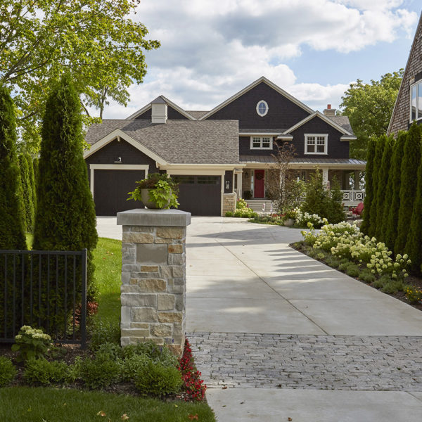 driveway-entrance-lined-with-arborvitae driveway with stone entry pillar