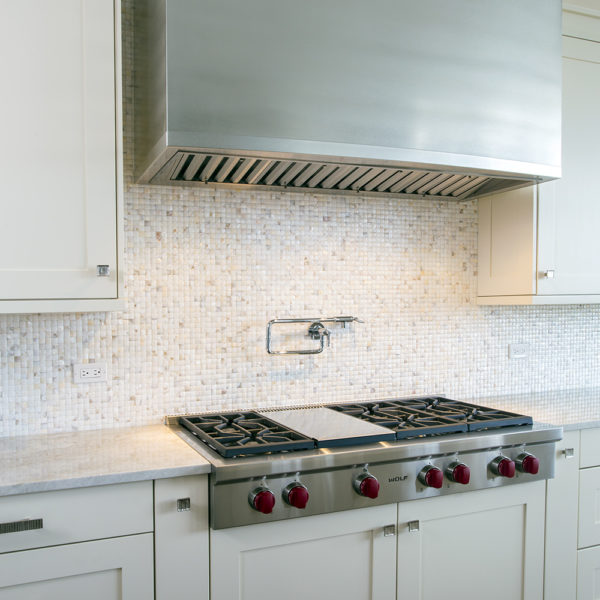 mosaic tile wall with massive stainless steel range hood