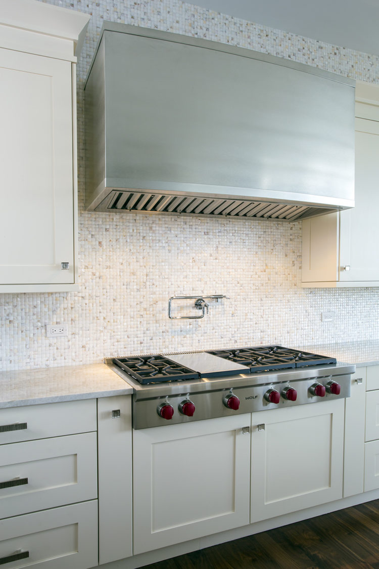 mosaic tile wall with massive stainless steel range hood