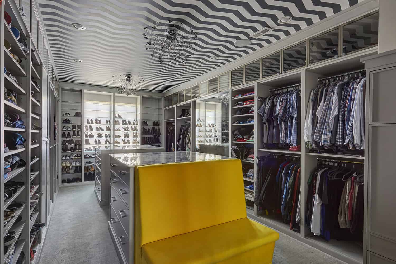 walkin closet with bright yellow bench and chevron ceiling detail