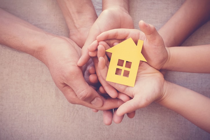 hands holding yellow house representing home warranty