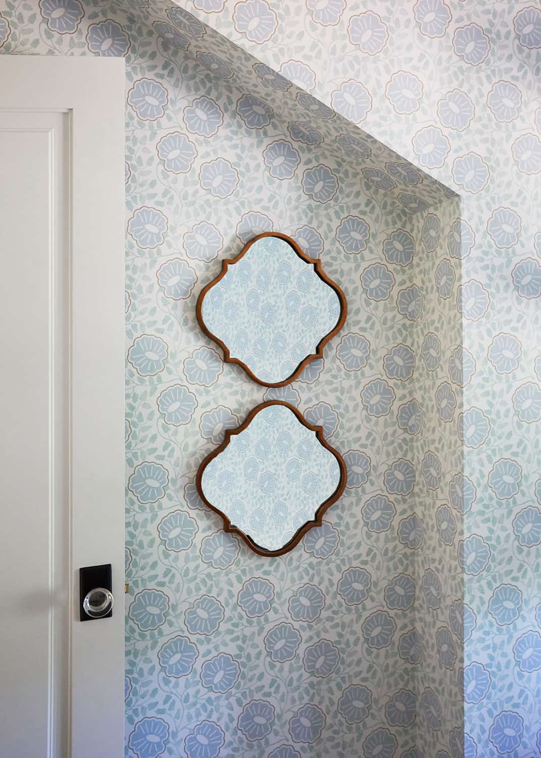 two mirrors on patterned wallpaper wall