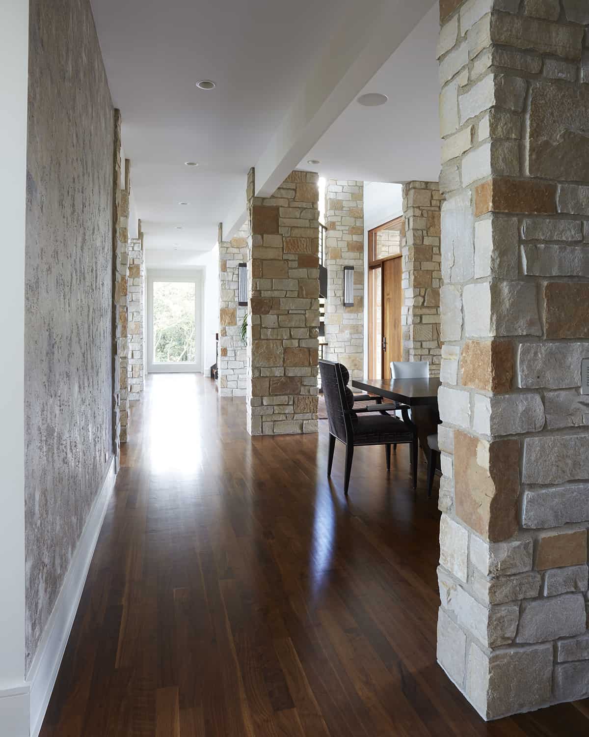 generous hallway with wood floor stone columns