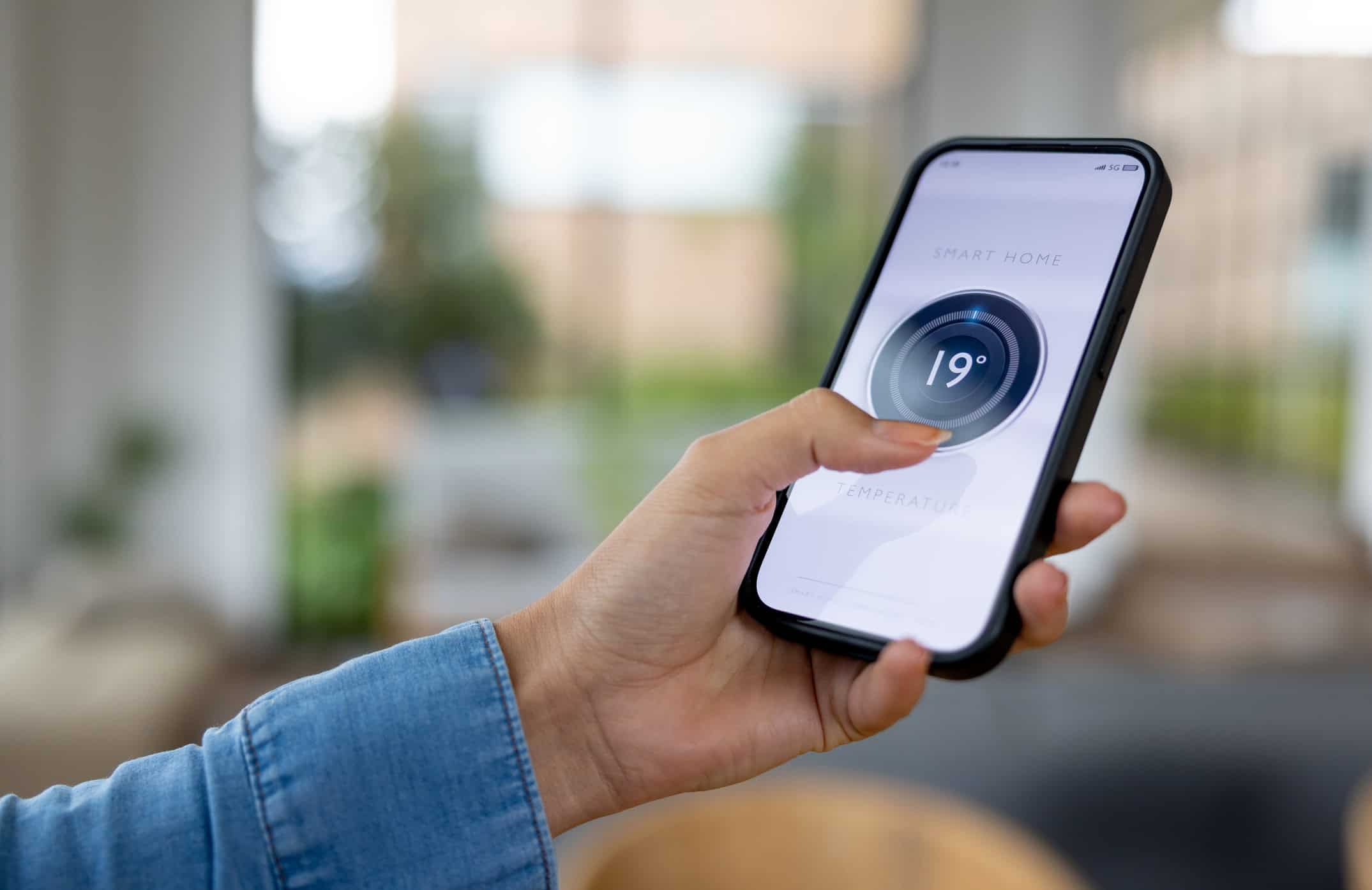 woman controlling thermostat with mobile phone