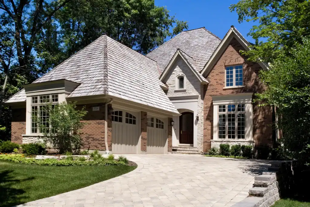 Picture of a beautiful brick and stone house with a steep roof and a paved driveway