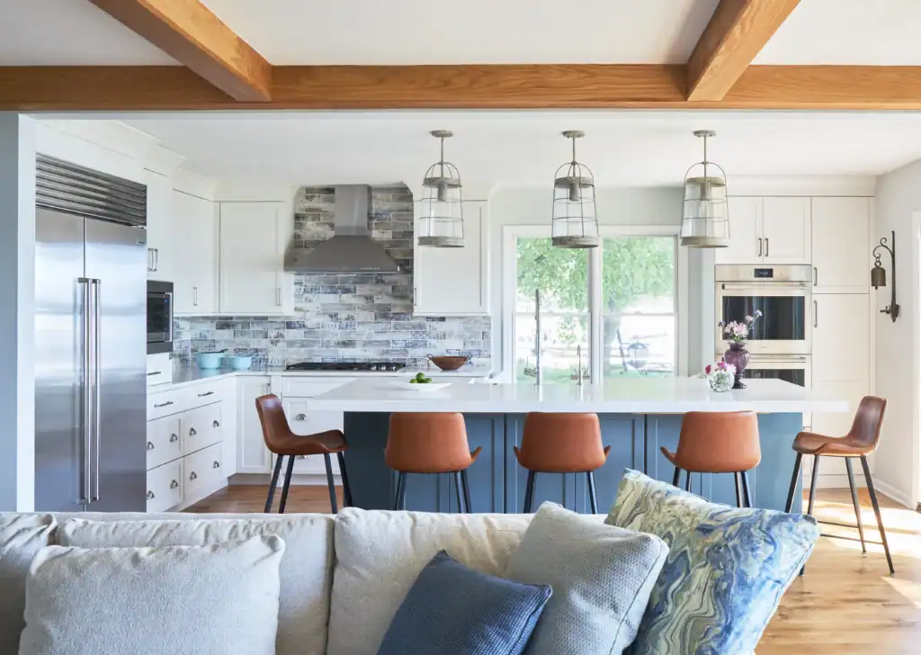 Picture of a bright kitchen featuring a blue island and exposed wooden ceiling beams