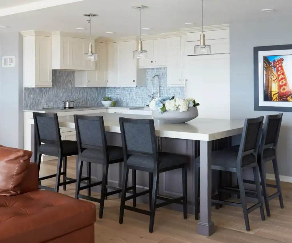 Picture of a contemporary kitchen with white cabinets and a grey island with black chairs