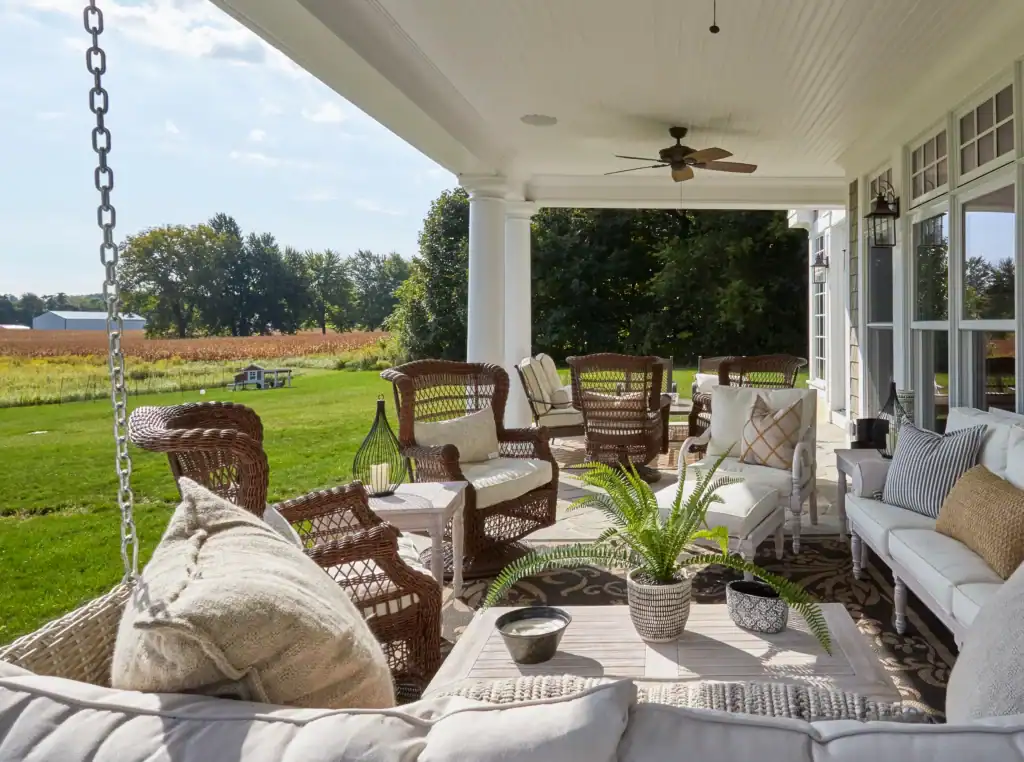 Picture of a covered outdoor patio with wicker furniture overlooking a lush green yard