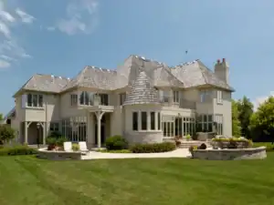 Picture of a large grey shingled house featuring white trim and a prominent rounded turret