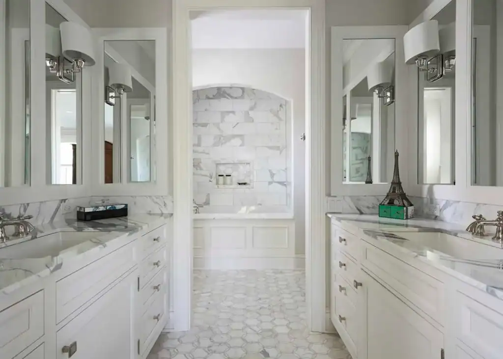 Picture of a bathroom with two white vanities facing each other and a doorway leading to a bathtub