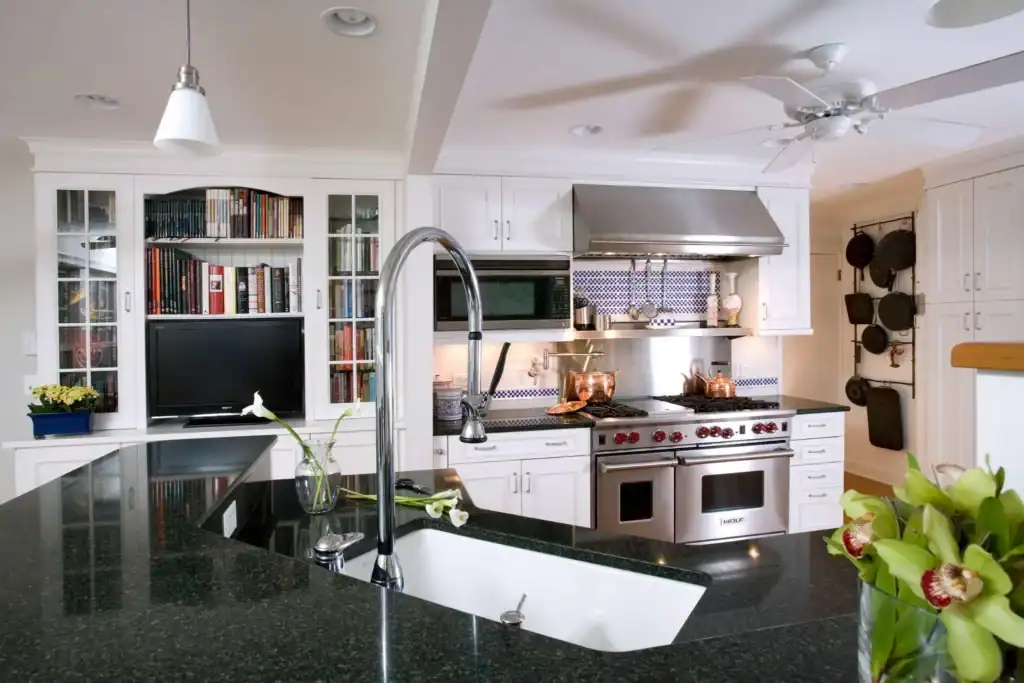Picture of a kitchen with white cabinets, dark countertops, and a stainless steel range