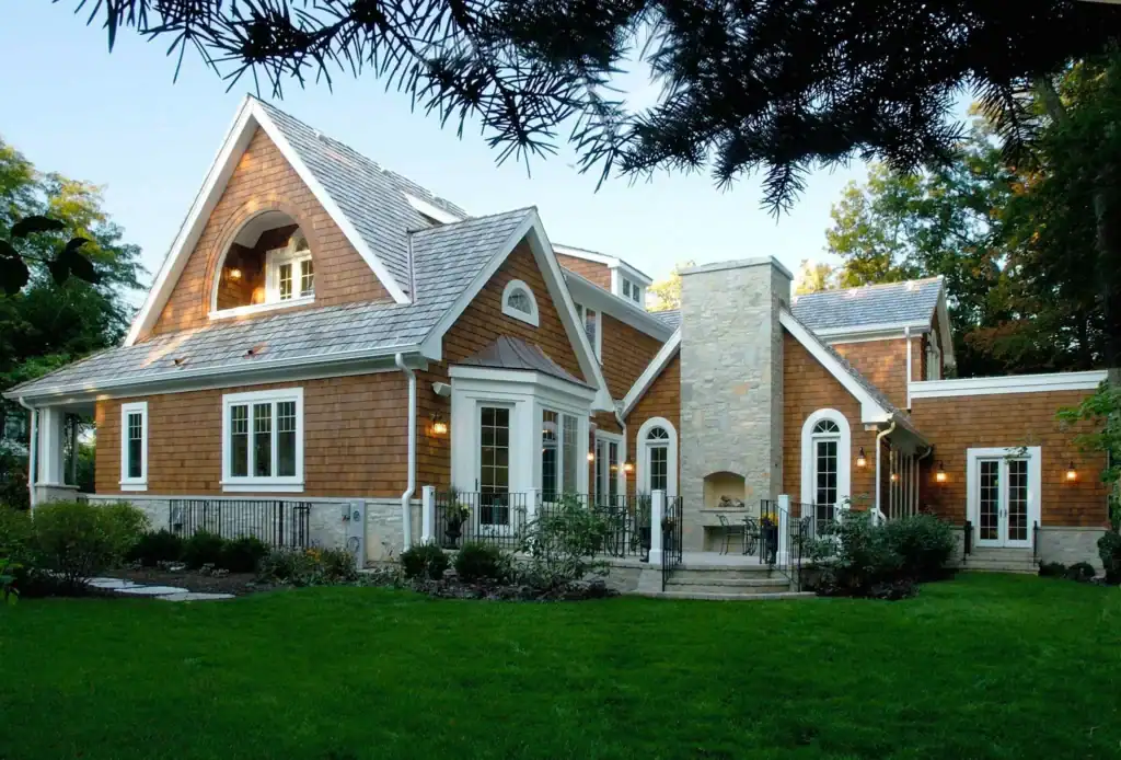 Picture of a large house exterior with brown shingle siding and a stone chimney