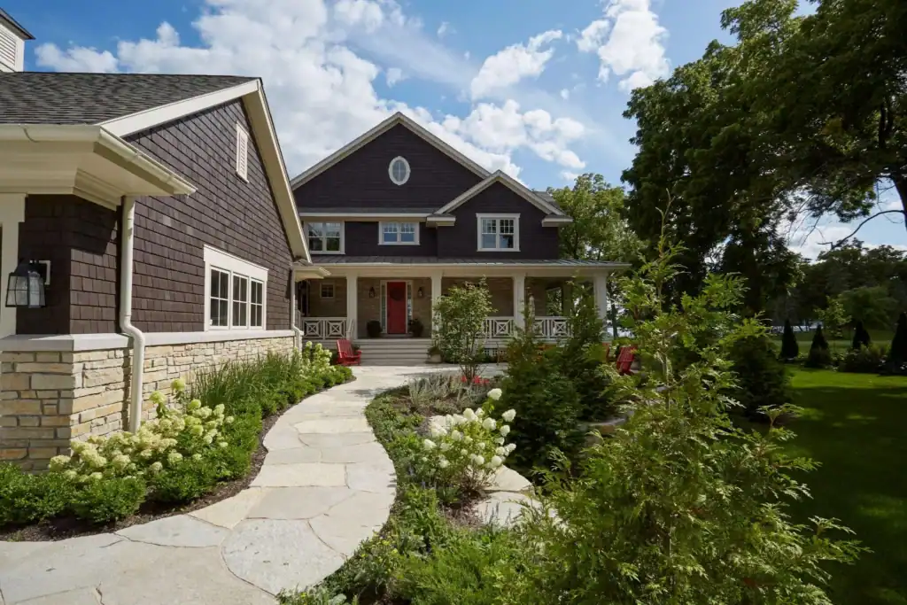 picture of a brown shingled house with red front door