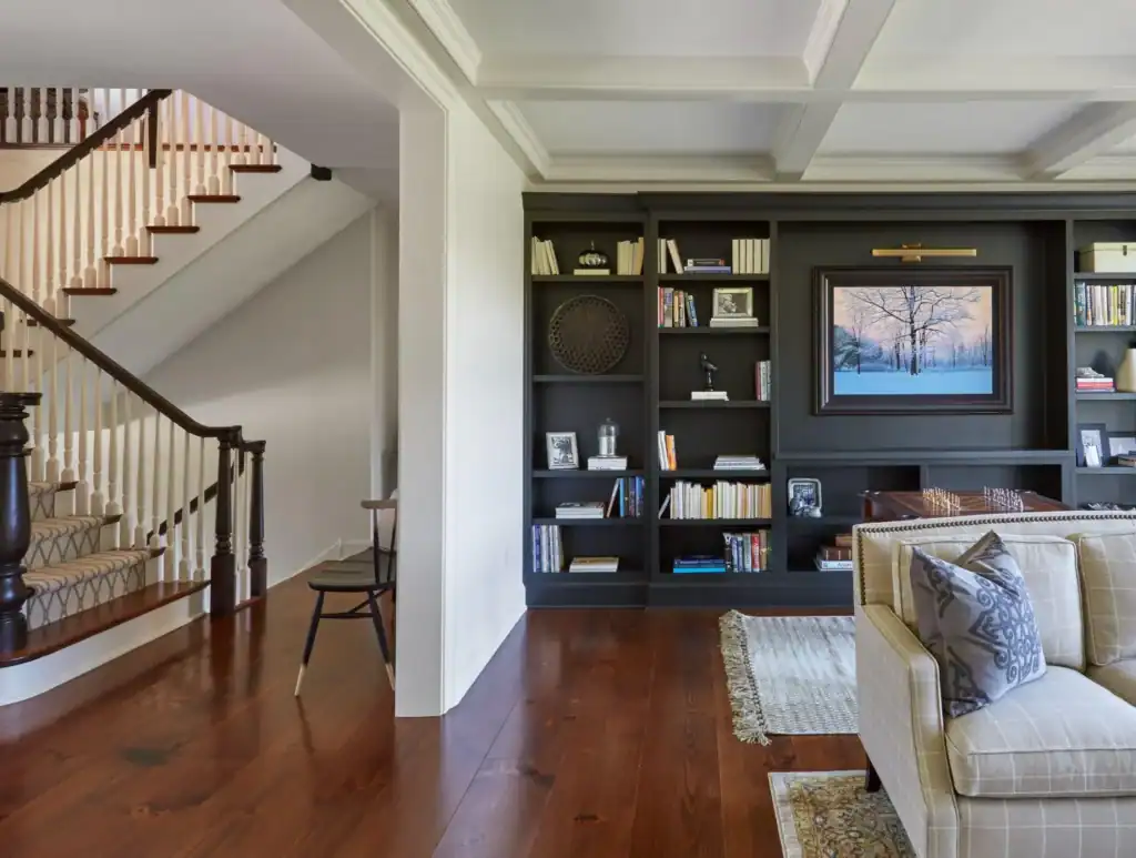 picture of a living room with black built in bookshelves and stairs